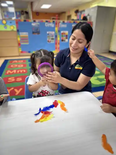 Preschool educator providing individualized attention and hands-on learning support to young children in a caring classroom environment